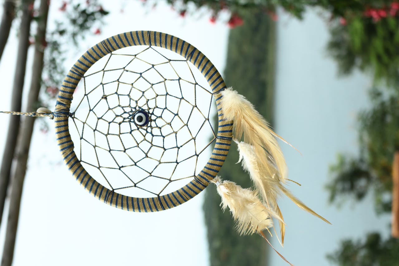 A beautiful handcrafted dreamcatcher with feathers hanging outdoors, capturing the essence of nature.