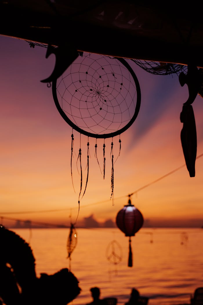Dreamcatcher hanging against a stunning beach sunset, creating a serene silhouette.